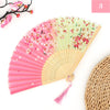 A pink and green vintage silk bamboo folding hand fan with a natural straw fan next to it.