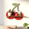 A wooden wall shelf shaped like a stylized olive branch in muted green mounted on a white wall.