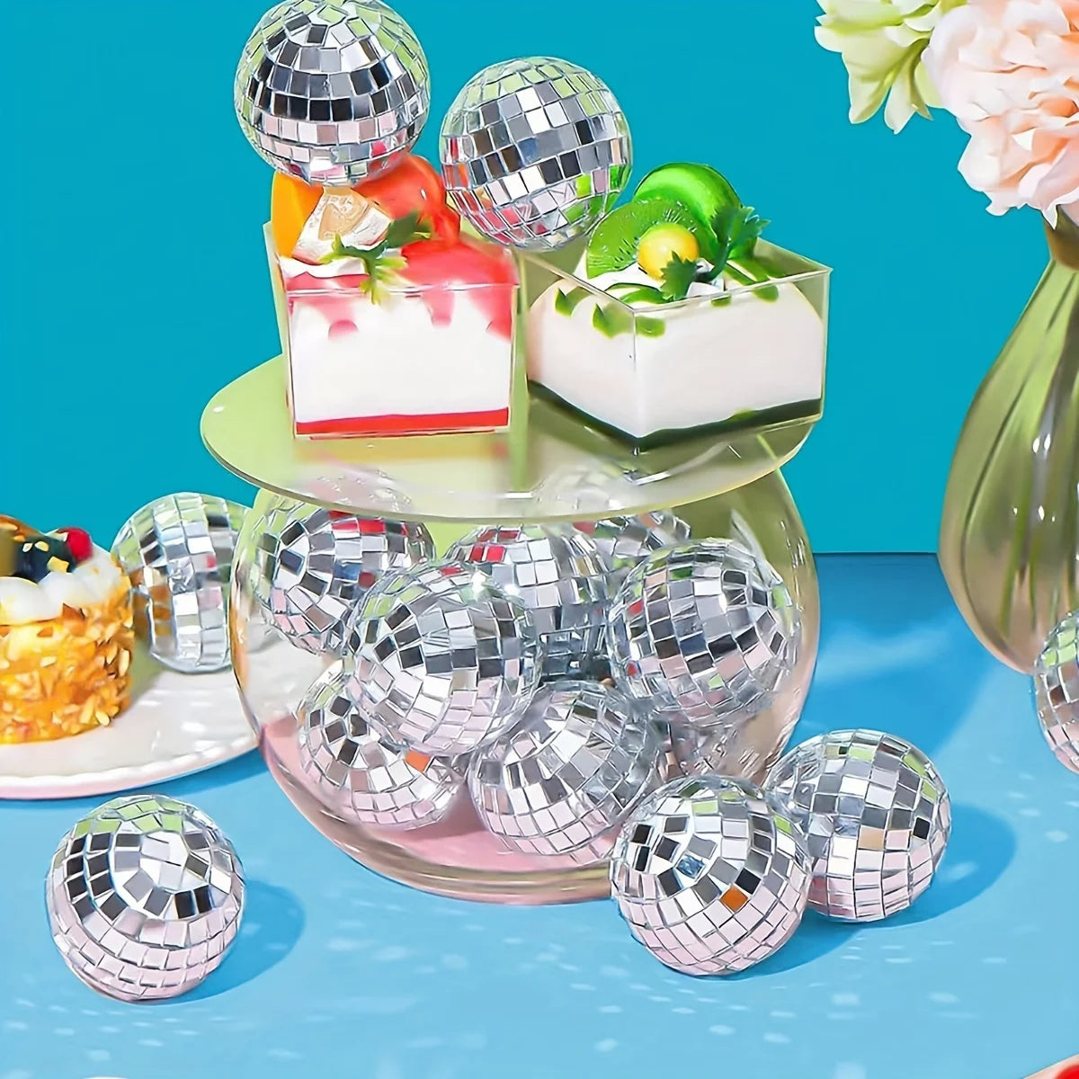 A set of ten silver disco ball ornaments arranged on a glass platter with small food items.