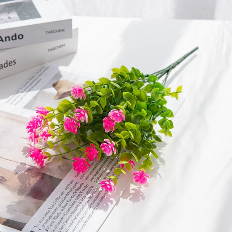 A branch of artificial eucalyptus with seven stems, featuring vibrant green leaves and pink flowers.