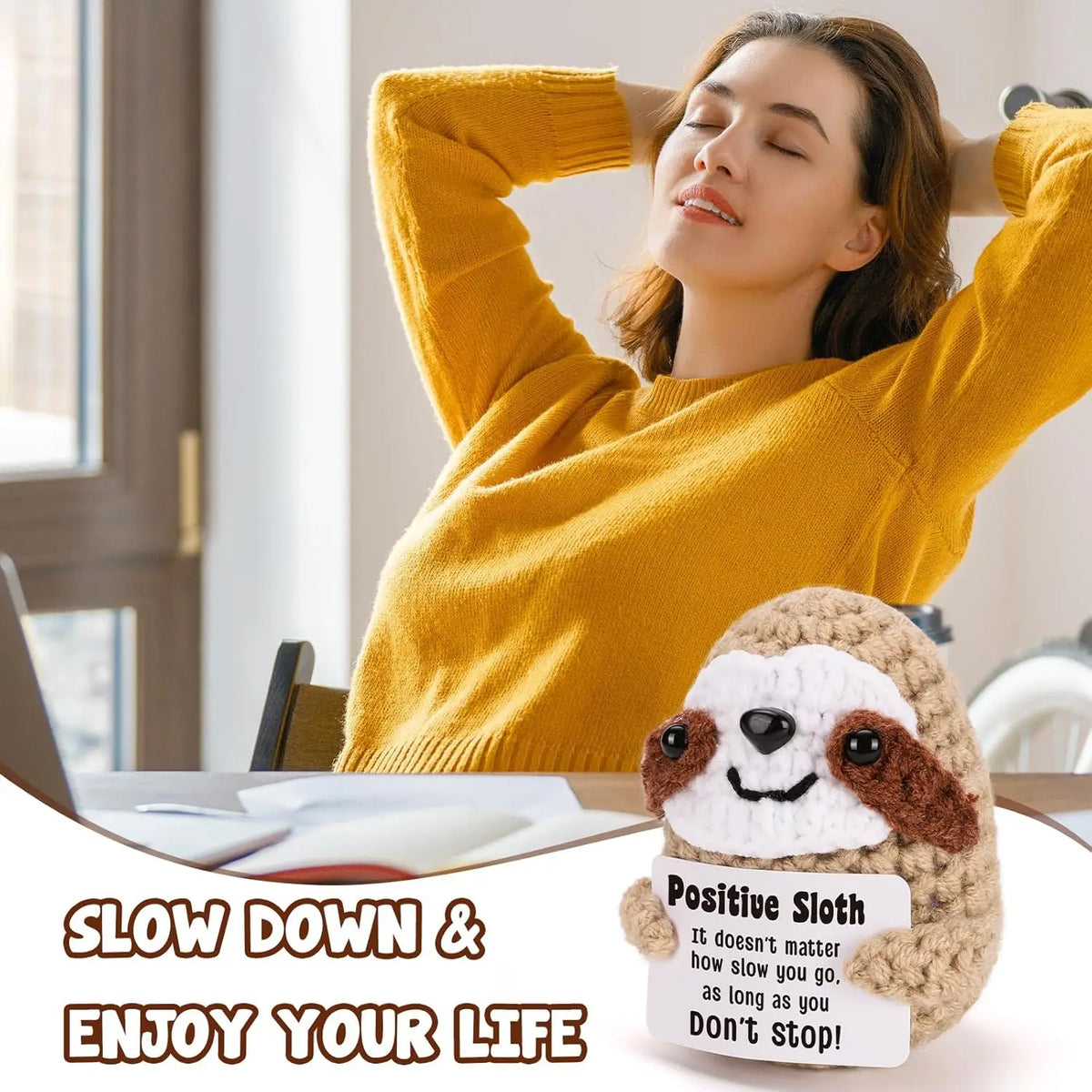 A woman in a yellow sweater is relaxing with her eyes closed while holding a handmade crochet sloth doll and a positive messa