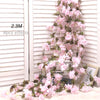 Artificial sakura flower garland with pink blossoms draped against a white slatted background