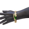 Gold and green St. Jude Cuban link bracelet worn on a dark hand.
