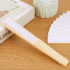 A light wood bamboo folding fan with white paper blades resting on a wooden surface.