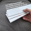 A hand holds several white 5mm paper foam boards for crafting or party decor.