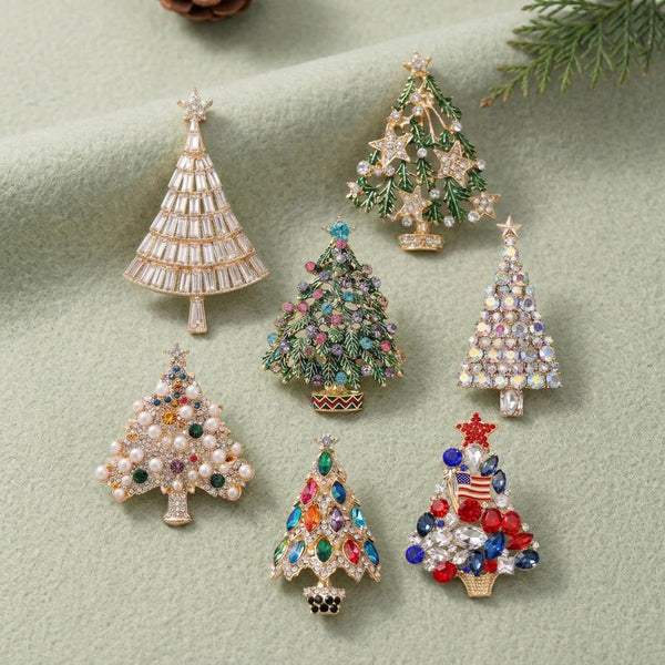 A collection of sparkling rhinestone Christmas tree brooches and pins on a light green background.