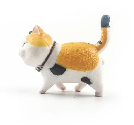 A white and orange 3D cartoon cat figurine with a black collar and tail, used as refrigerator magnets.