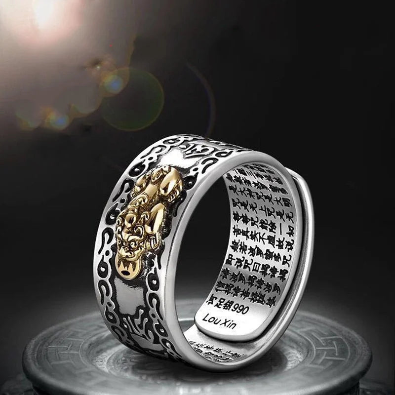 Silver ring featuring a gold pixiu design and detailed coin engravings on a dark background.