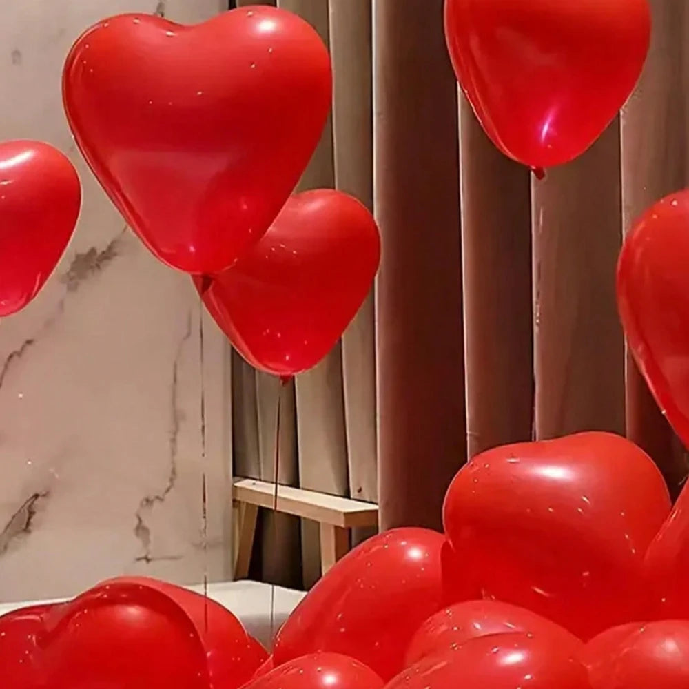 A cluster of red heart-shaped latex balloons hanging in a soft, indoor setting.