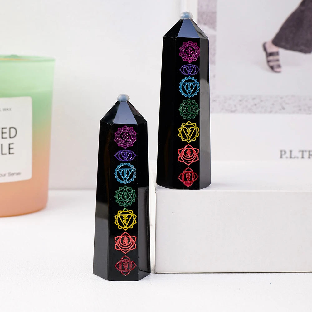 A tall black obsidian crystal tower with various colored floral designs stands on a white box.