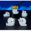 A set of seven white ghost resin ornaments, including a yellow luminous ornament, displayed against a dark blue background.