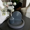 A gray silicone mold for crafting is displayed on a dark surface next to a sprig of frosted greenery.