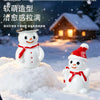White resin snowman figurines with red accents standing in a snowy outdoor setting