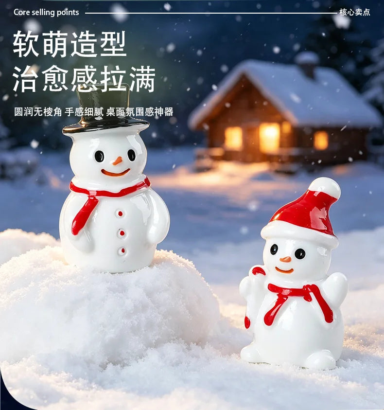 White resin snowman figurines with red accents standing in a snowy outdoor setting
