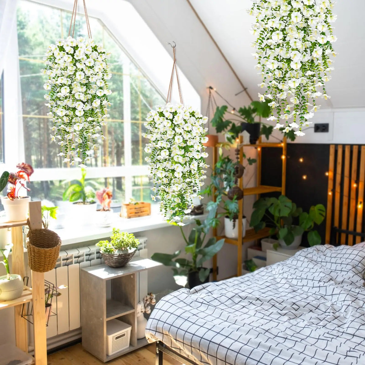 A bed decorated with white and black patterned bedding in a bright room featuring hanging artificial morning glory flowers.