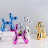 A collection of shiny resin balloon dog sculptures in blue, silver, and gold on a white surface.