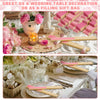 Pink paper hand fans displayed with gift bags and thank you cards on a rustic wooden surface.