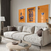 A modern living room featuring a light sofa and three framed art prints with the text LUCKY YOU on an orange background.
