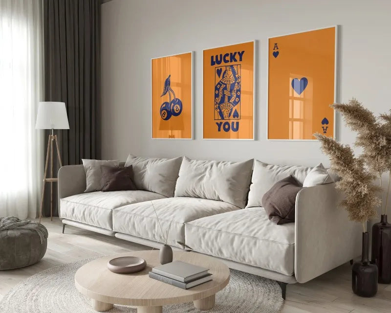 A modern living room features a light sofa, wooden coffee table, and framed art prints with blue and orange tones.