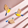 Three vintage wooden bird wall decorations in yellow and blue against a pink background.