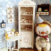 A white wooden cabinet displaying a handcrafted miniature mushroom tableware set for dollhouses.