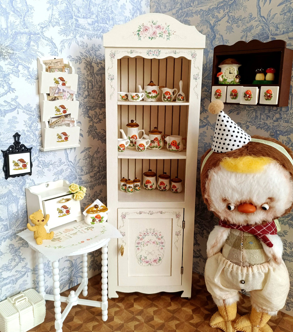 A white wooden cabinet displaying a handcrafted miniature mushroom tableware set for dollhouses.