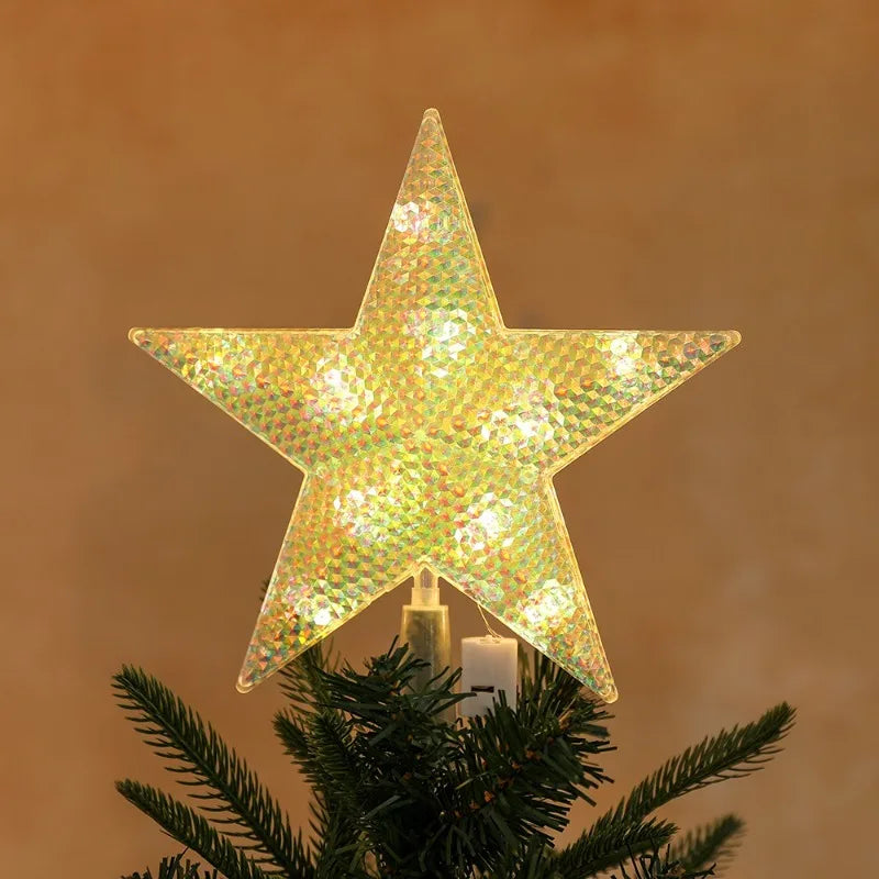 A sparkling, geometric star light fixture is placed on a green pine branch.