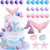 A mermaid cake topper set featuring various sea creatures, shells, and colorful fins on a blue and pink tiered cake.