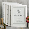 A set of five white wooden photo frames with black line art designs displayed on a gray surface.
