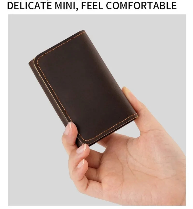 A hand holds a dark brown vintage leather mini card holder used as a cable organizer.