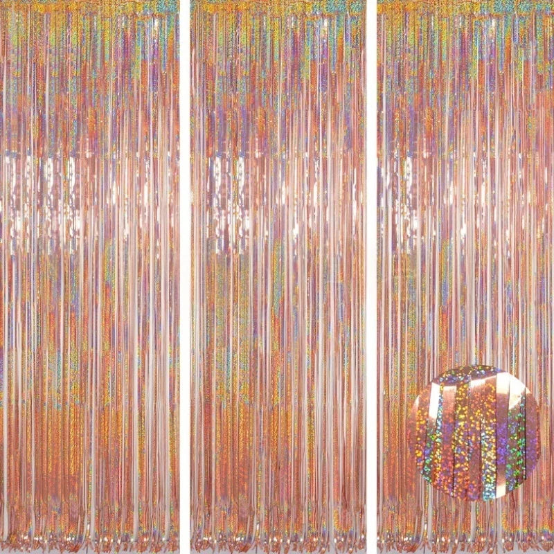 A vertical backdrop featuring long strands of metallic foil tinsel fringe in shades of orange, gold, and iridescent colors.