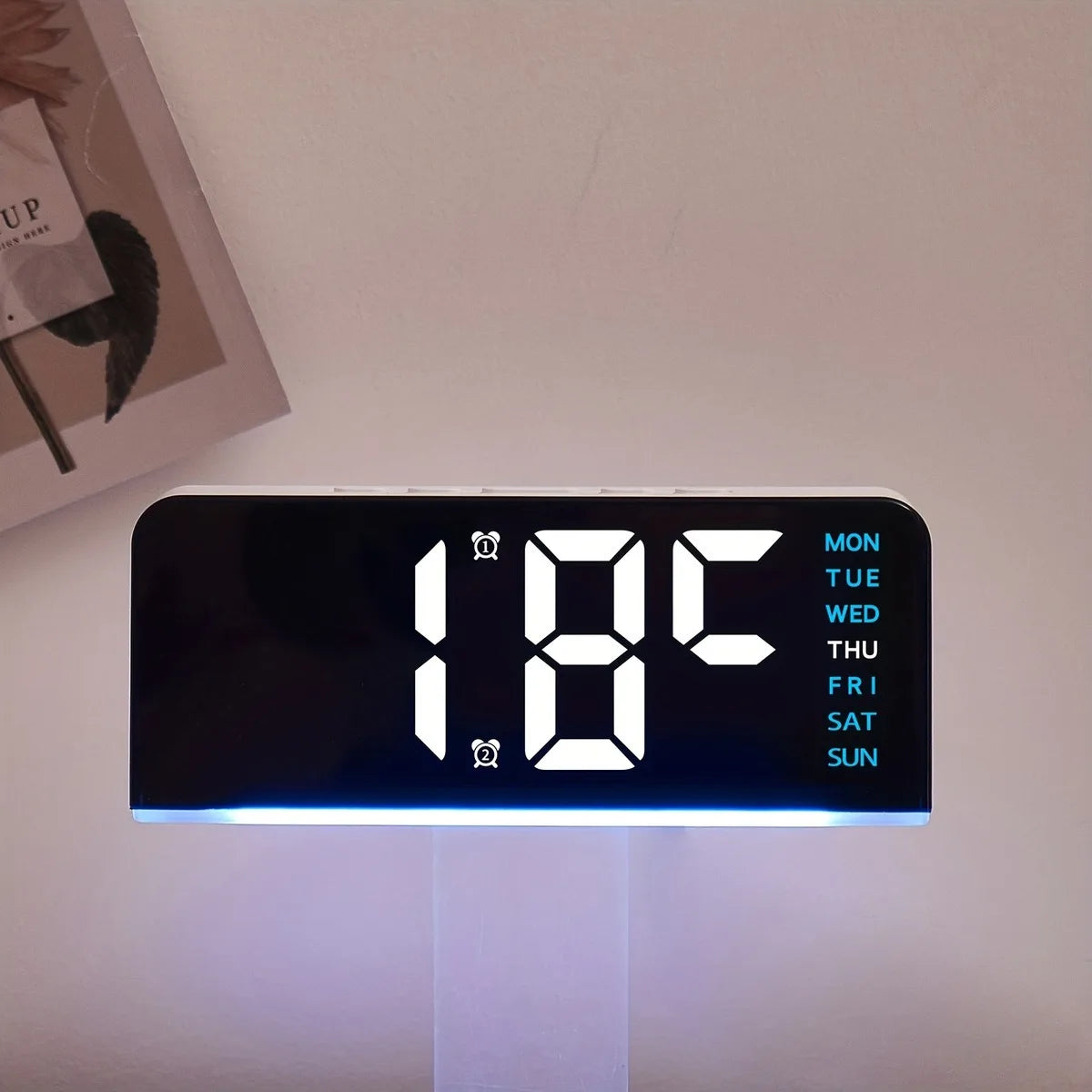 A black LED digital alarm clock displaying 1.8C with a blue ambient glow and days of the week.