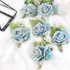 A set of six dusty blue silk rose boutonnières featuring greenery and white filler flowers.