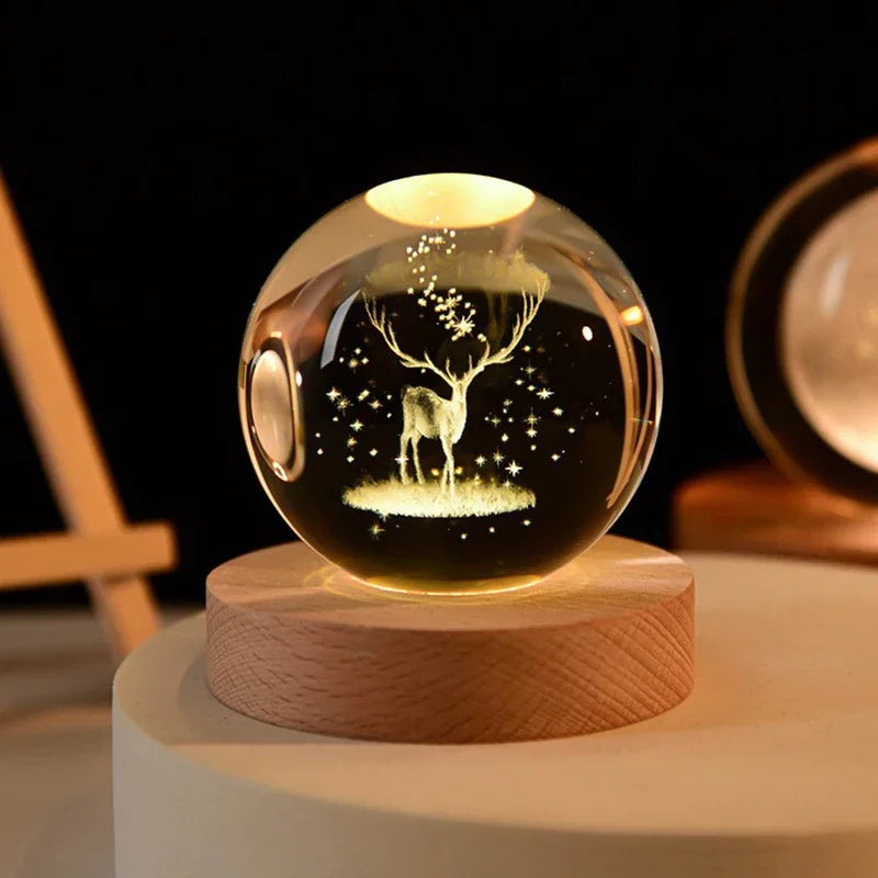 A glass crystal ball with a tree silhouette engraved inside, resting on a wooden base.