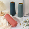 Three modern plastic cylindrical vases in muted green and coral tones displayed on a white surface.
