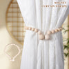 Magnetic curtain straps made of wooden beads used as tiebacks for a white sheer curtain.