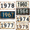 A collection of vintage aluminum license plates showing various years like 1960, 1964, 1967, 1978, 1974, 1977, and 1979.