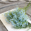 A bouquet of light blue artificial gypsophila flowers displayed on a white surface.