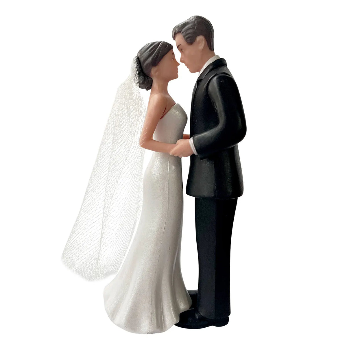 A wedding cake topper featuring an elegant bride and groom figurine in white and black attire.
