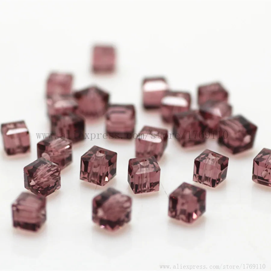 A scattering of square cut glass crystal beads in a dusty rose color on a white background.