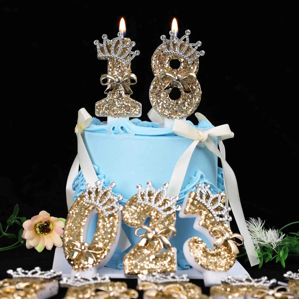 A light blue cake decorated with gold glitter number toppers and candles on a black background.