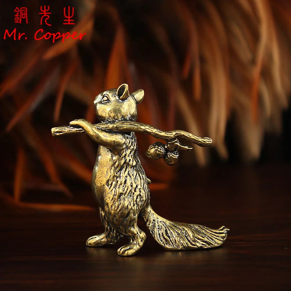 A vintage brass squirrel figurine standing on a dark wooden surface.