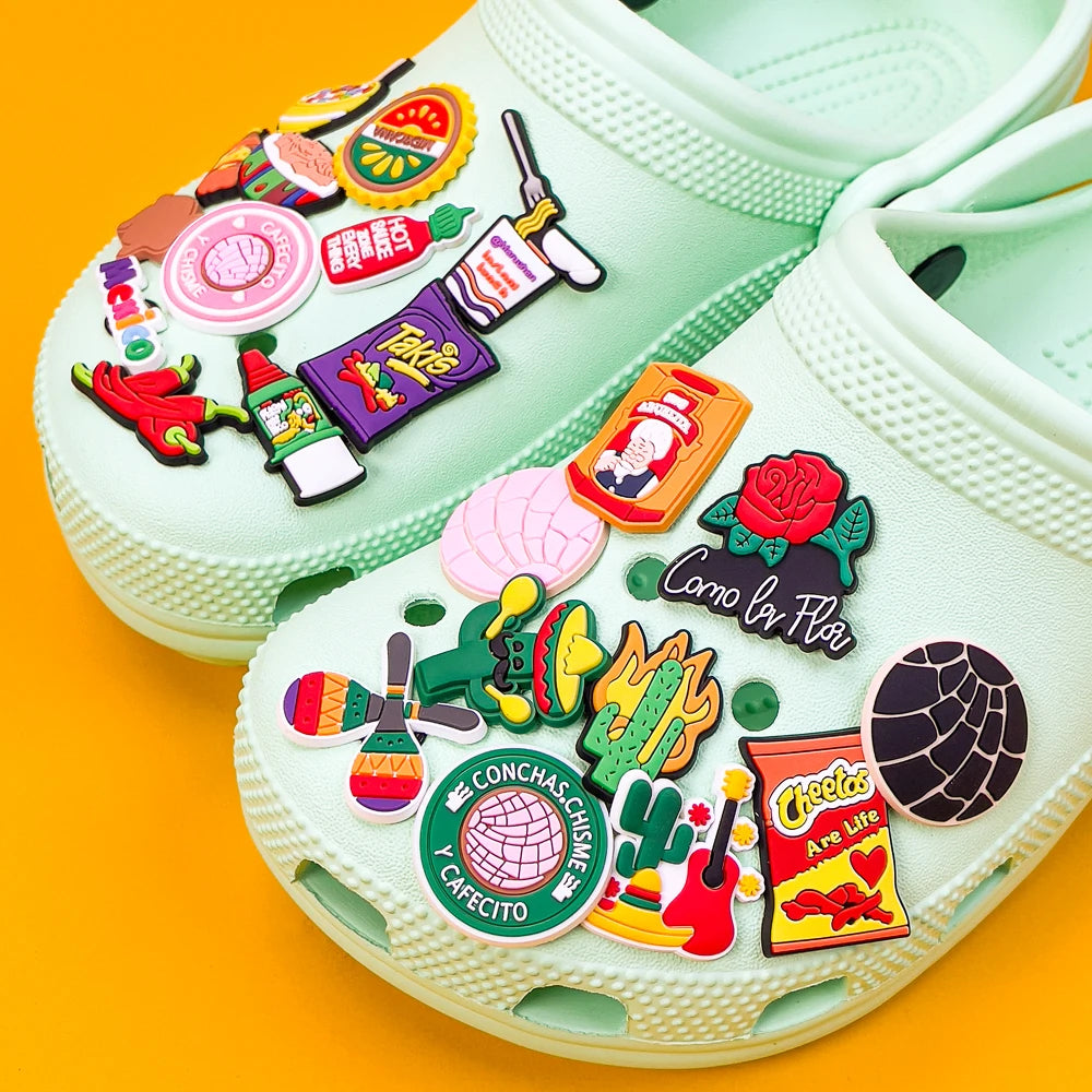 A pair of light green PVC shoes decorated with colorful Mexico style charms and stickers.