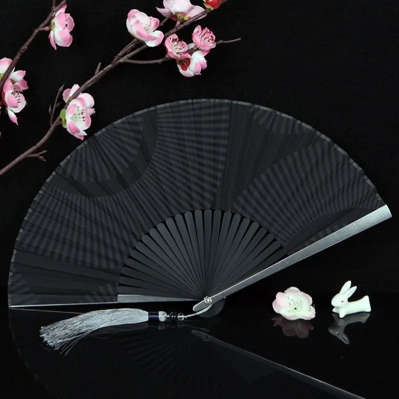 A black titanium alloy folding hand fan with a sheer mesh surface is displayed against a dark background.