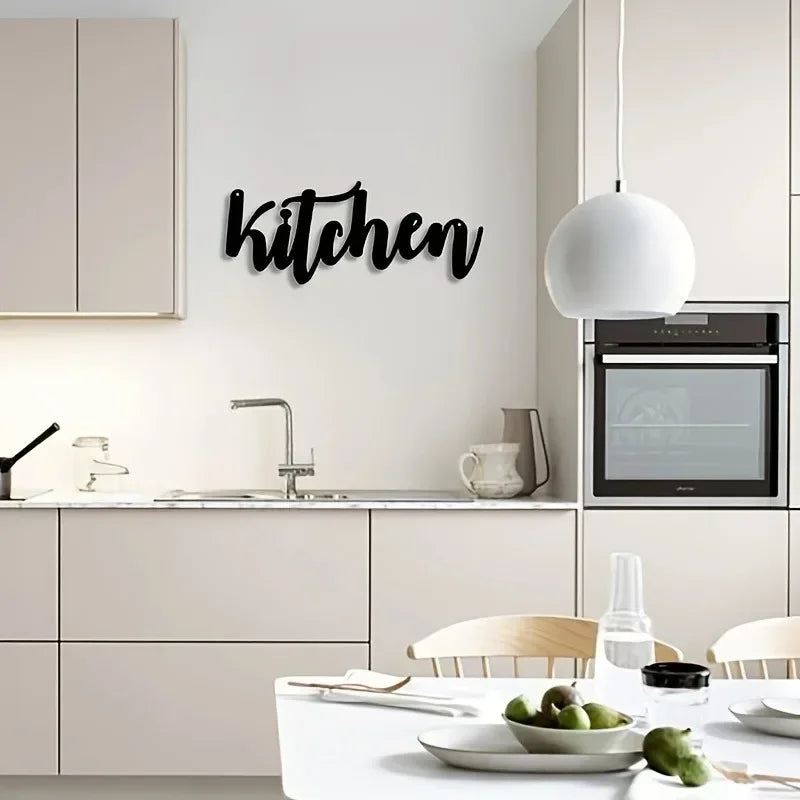 Minimalist metal letter wall art spelling the word kitchen on a white wall above a modern kitchen counter.