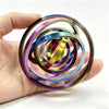 A hand holds a stack of colorful, rotating ball spinner fidget toys with iridescent and metallic finishes.