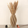 A tall arrangement of dried pampas grass in a textured wave vase with soft beige tones.
