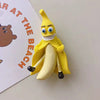 A yellow banana fruit fridge magnet with a wide, smiling mouth and white teeth is shown next to text that reads 'AR AT THE BE