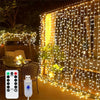 A string of warm white LED fairy lights hangs vertically across a wooden deck, illuminating a yellow curtain backdrop.