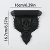 A black ornate gothic wall shelf featuring intricate carvings of a skull and foliage.